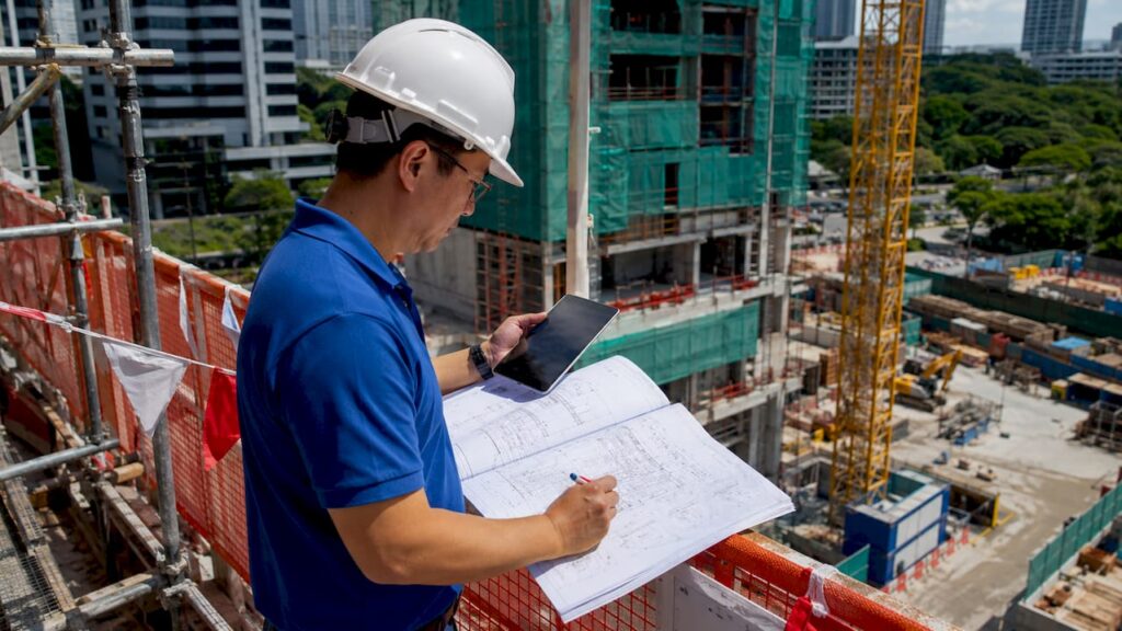 Engineer inspecting building with plans and tablet