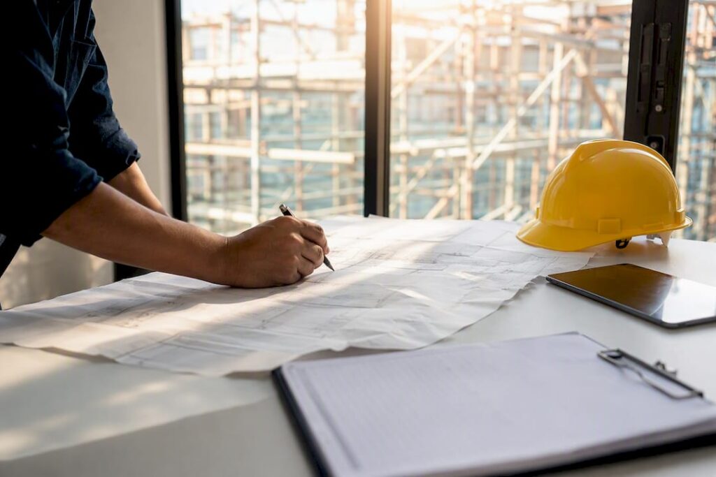 Hands marking up construction safety blueprint