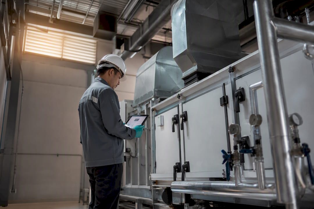Technician inspecting HVAC asset in plant room
